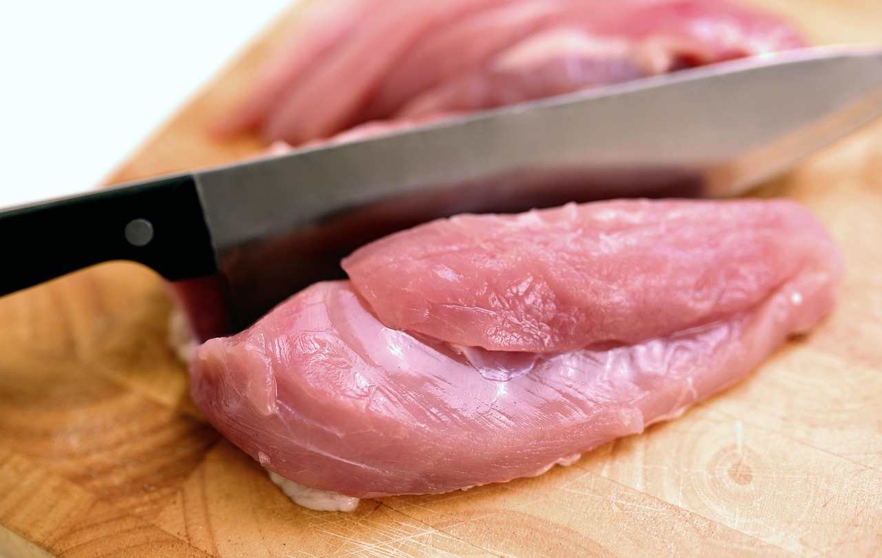knife slicing raw chicken